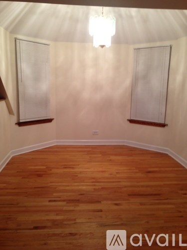 A room with wooden floors and two windows.