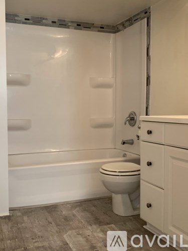 A bathroom with a toilet, tub, and cabinet.