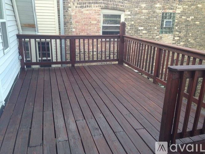 A wooden deck with a railing and a brick wall in the background.