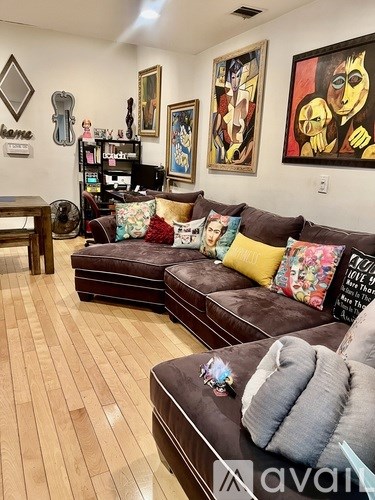 A living room with a brown couch and a painting on the wall.