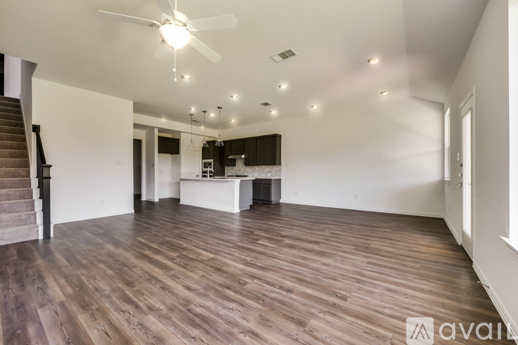 A spacious room with wooden flooring and a ceiling fan.