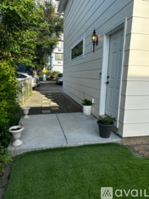 A white house with a grey door and a small garden.