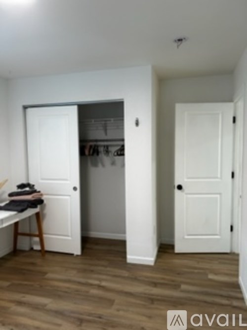 A room with a white door and a wooden floor.