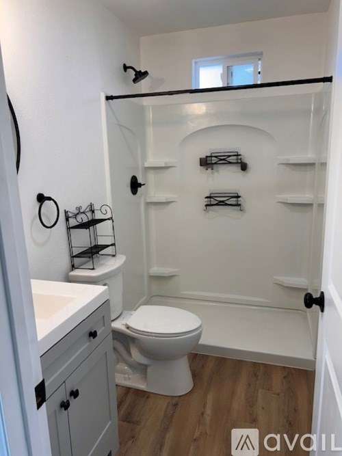 A white bathroom with a toilet, sink, and shelves.