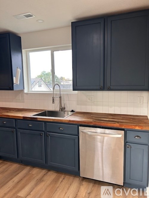 A kitchen with dark cabinets and a wooden countertop.