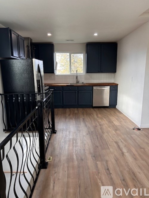 A kitchen with black cabinets and a wooden floor.