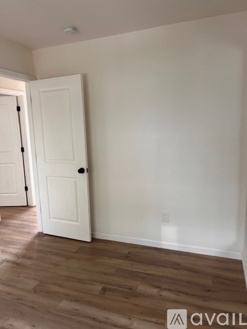 A room with a white door and wooden flooring.