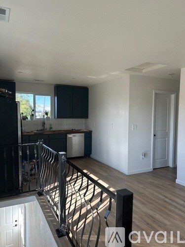 A modern kitchen with a black fridge and a wooden floor.