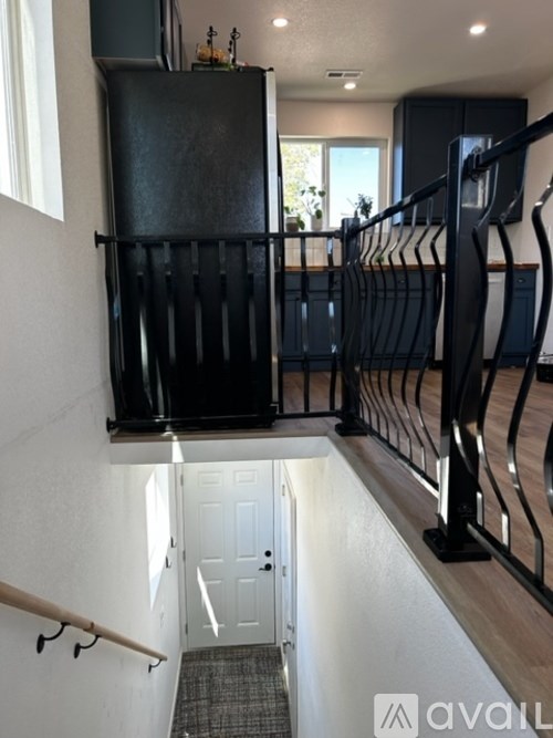 A black refrigerator is in a kitchen with a white door.