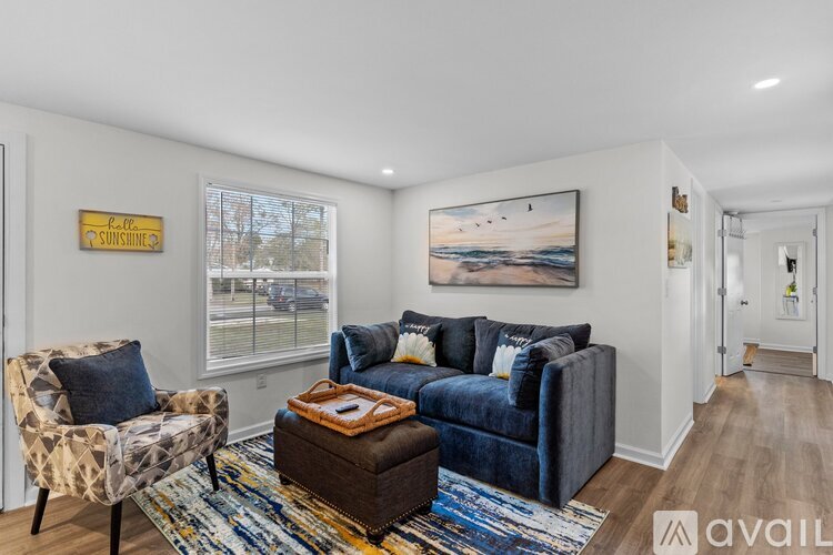 A living room with a blue couch, a chair, and a rug.