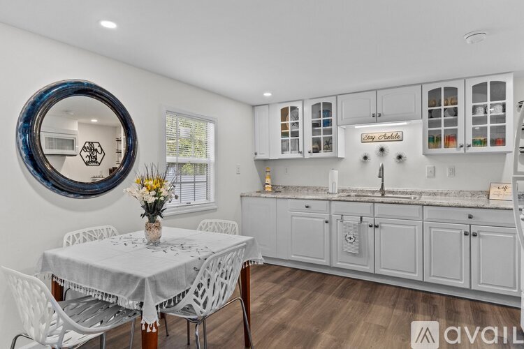 A kitchen with a table and chairs in the foreground and a large mirror on the wall.