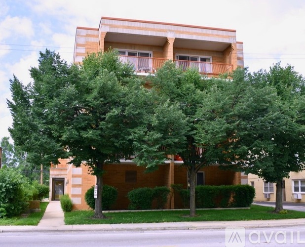 A building with a brown and beige exterior is surrounded by green trees.