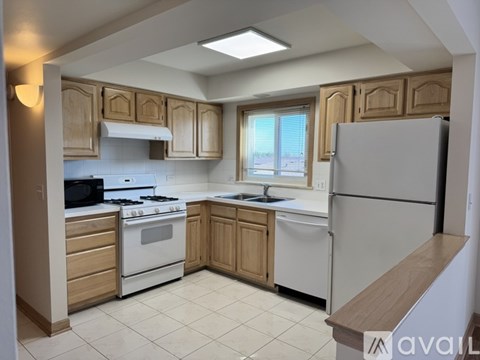 A kitchen with white appliances and wooden cabinets.