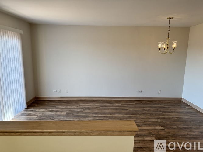 A room with a wooden floor and a chandelier hanging from the ceiling.