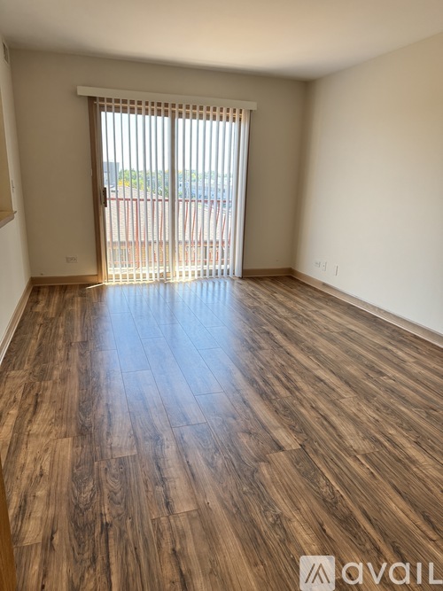 A room with wooden flooring and a window with blinds.