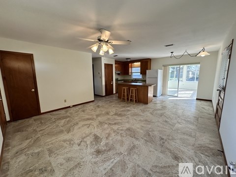 A spacious room with a ceiling fan and marble flooring.