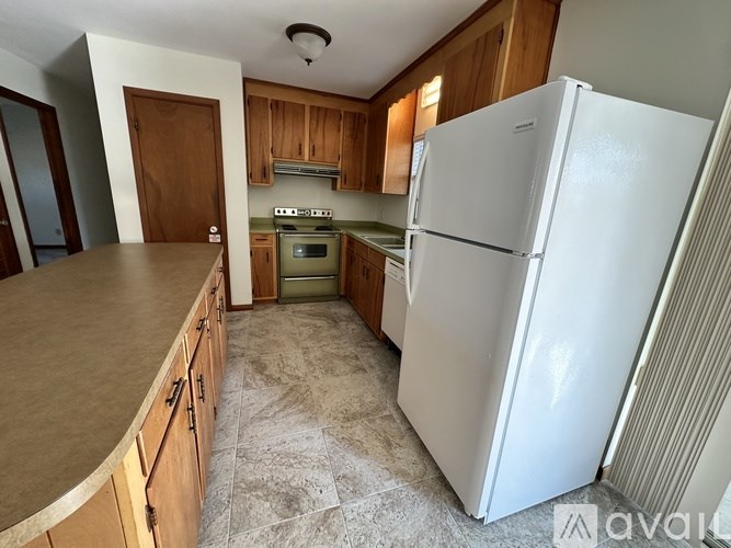 A kitchen with a white refrigerator and wooden cabinets.