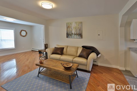 A living room with a couch, coffee table, and a painting on the wall.