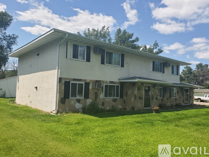 A house with a white exterior and a stone wall is available for rent.