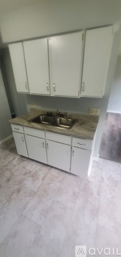 A kitchen with white cabinets and a marble countertop.