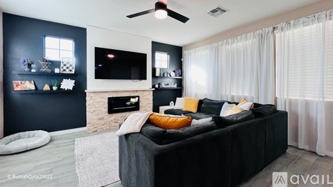 A modern living room with a black couch and a fireplace.