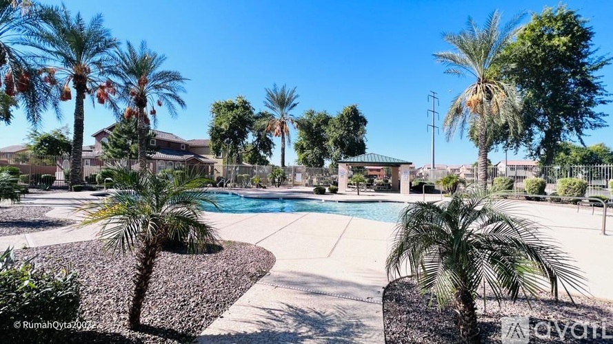 A pool surrounded by palm trees and a house in the background.