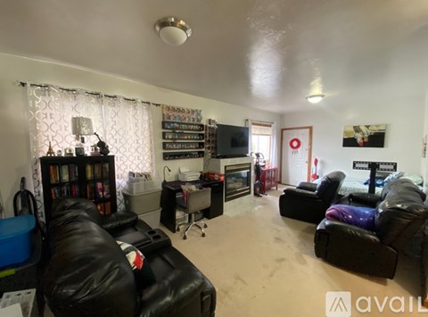 A living room with black leather couches and a television.