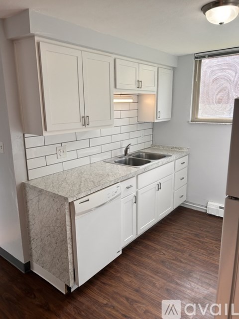 A kitchen with white cabinets and a marble countertop.