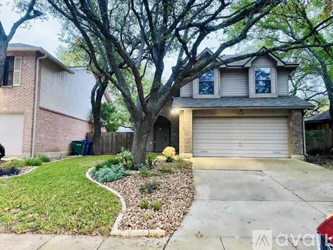 A house with a driveway and a tree in front.