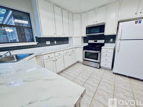 A kitchen with white cabinets and a marble countertop.