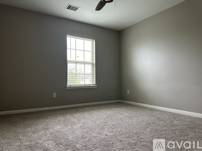 A room with a carpeted floor, a window, and a ceiling fan.
