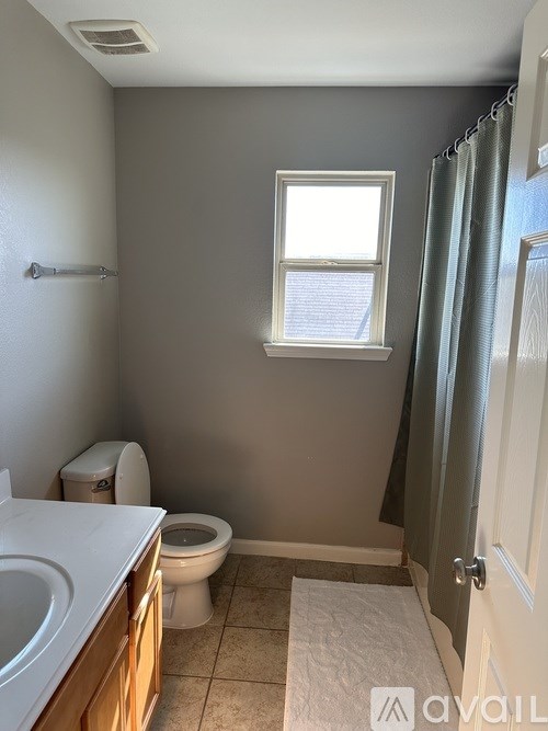 A bathroom with a toilet, sink, and window.