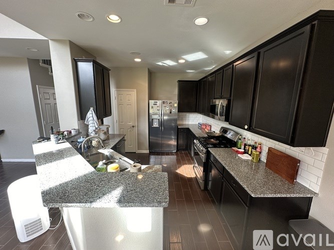 A kitchen with black cabinets and a granite countertop.