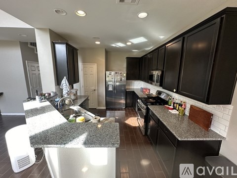 A kitchen with black cabinets and a granite countertop.
