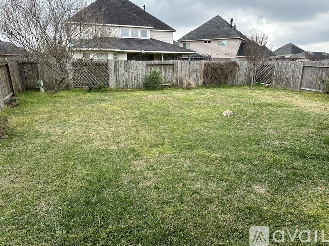 A backyard with a fence and a house in the background.