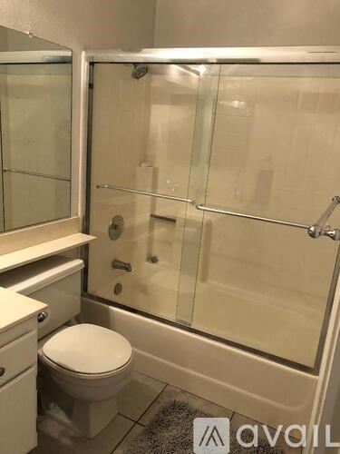 A bathroom with a toilet, sink, and glass shower door.