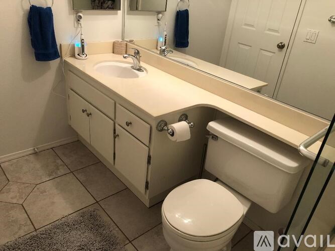 A bathroom with a toilet, sink, and mirror.