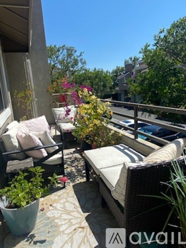A patio with a couch, chairs, and a table with flowers.