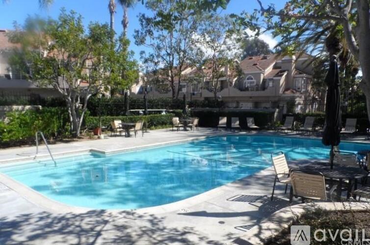 A pool surrounded by trees and chairs.