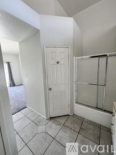 A bedroom with a large bed, a chair, a wooden cabinet, and a window with a view of the city.
