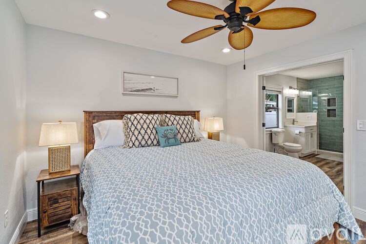 A bedroom with a bed, nightstand, and a ceiling fan.