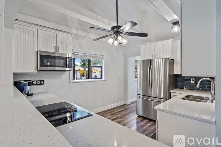 A modern kitchen with a stainless steel refrigerator and a ceiling fan.