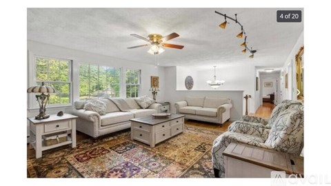 A living room with a white ceiling fan and a rug on the floor.