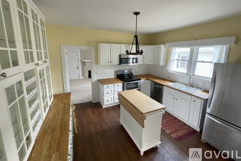 A kitchen with white cabinets and a wooden island.