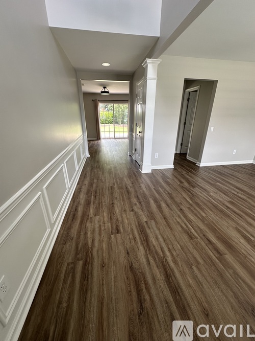 A long hallway with wood floors and white walls.
