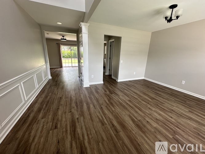 A spacious room with wood flooring and white walls.