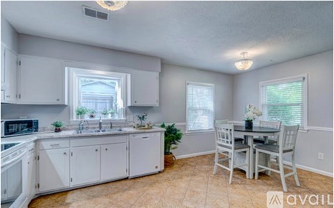 A kitchen with white cabinets and a dining table with chairs.