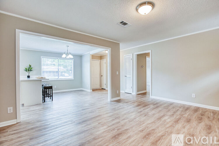 A spacious room with wooden flooring and a window with a view of a balcony.
