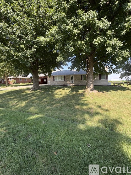 A grassy area with trees and a house in the background.