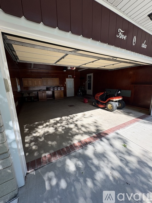 A garage with a red and black lawn mower in it.